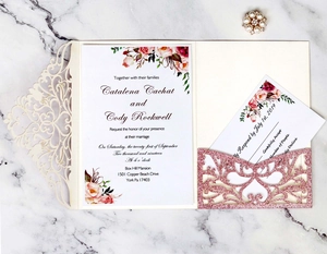 Detailed four-piece laser cut wedding invitation set with floral inner card on marble background
