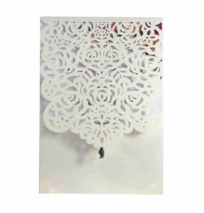 Detail showing laser cut rose patterns and teardrop crystal on an ivory wedding invitation