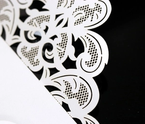 Macro shot of laser-cut white lace paper featuring intricate floral scrollwork patterns