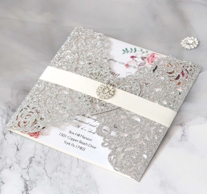 Détail de l'invitation de mariage découpée au laser avec ruban blanc et boucle en strass
