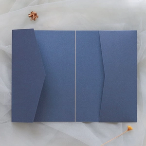 Détail de l'invitation en papier perlé bleu marine avec découpe laser sur fond de tulle blanc