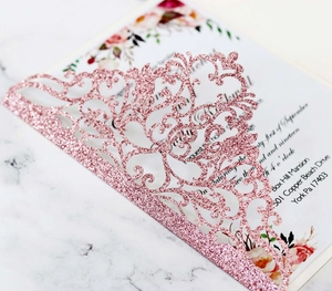 Close-up of laser-cut glitter paper invitation cover with elegant floral patterns
