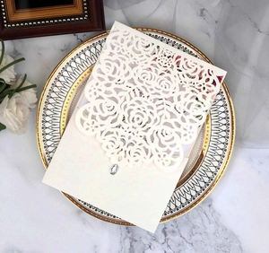 Detail view of laser cut ivory wedding invitation with floral pattern and rhinestone