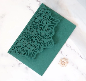 Detail of dark green laser-cut lace invitation envelope with elegant pearl accent