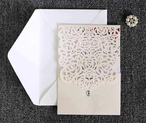 Detailed laser-cut rose pattern on cream wedding invitation with pearl accessory