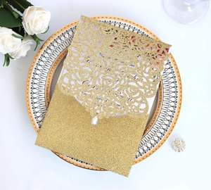 Λεπτομέρεια χρυσού glitter προσκλητηρίου γάμου laser-cut με φλοράλ σχέδιο και κρύσταλλο