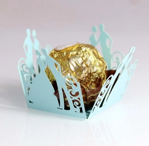 Close-up of laser-cut light blue cupcake wrapper with romantic couple silhouette
