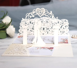 Detail of laser cut wedding invitation with 3D bride and groom silhouette and inner card