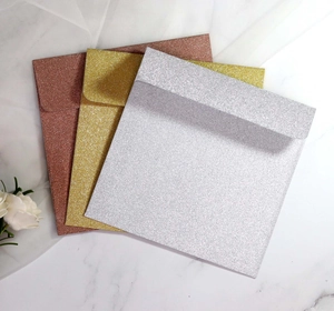 Close-up of glitter square envelopes in gold silver and rose gold for wedding invites