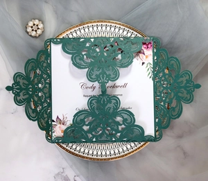 Detailed laser-cut floral pattern on dark green lace wedding invitation with white insert