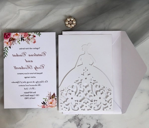 Detail of laser-cut wedding invitation with bridal silhouette and pearl floral brooch