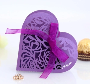 Detail of purple laser-cut wedding favor box with rose patterns and ribbon bow