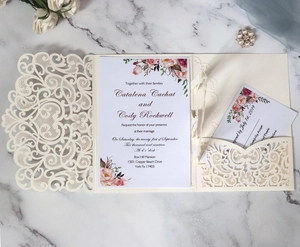 Detailed laser-cut lace wedding invitation with watercolor floral inner cards on marble
