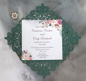 Detailed laser cut lace pattern on dark green wedding invitation with floral insert