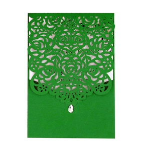 Detail of green laser-cut wedding invitation with intricate rose patterns and a teardrop gem