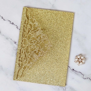 Detail of laser-cut floral patterns on a glittery gold business invitation card