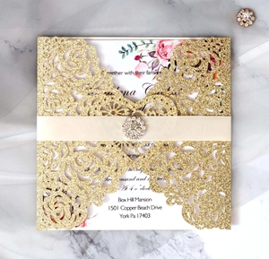Détail de l'invitation de mariage dorée pailletée avec ruban blanc et carte florale