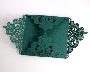 Detailed macro shot of dark green laser-cut wedding invitation with intricate lace patterns