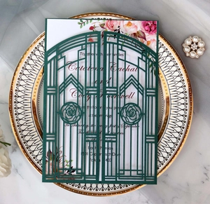 Intricate laser-cut dark green wedding invitation on elegant marble with pearl accents