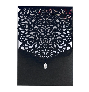 Detail of black laser-cut rose wedding invitation with droplet crystal and floral insert