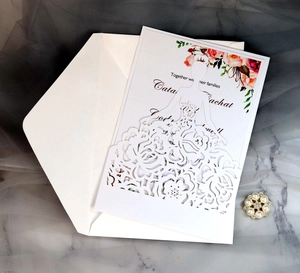Macro shot of laser-cut floral wedding invitation with rose pattern on marble background