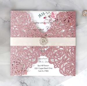 Détail de l'invitation de mariage découpée au laser avec rose pailletée rose et ruban