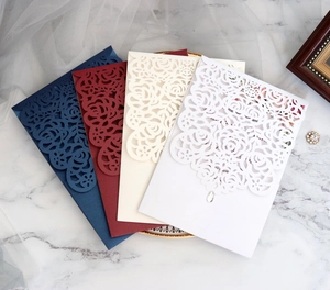 Detailed view of laser cut floral wedding invitations in navy, burgundy, beige, and white