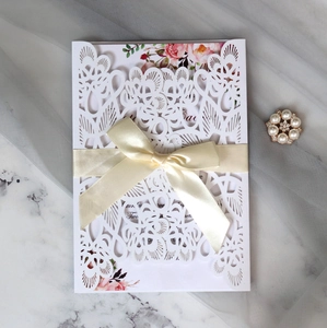 Elegant laser-cut wedding invitation with champagne silk ribbon and floral insert card
