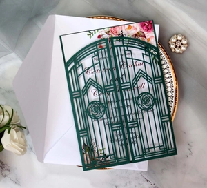 Detail of laser-cut forest green wedding invitation with elegant floral card and envelope