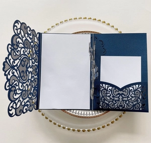 Macro view of navy blue laser-cut floral invitation cover with white paper inserts