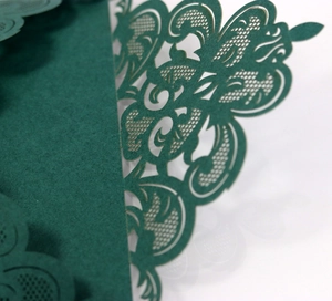 Macro shot of laser-cut dark green floral pattern and texture on elegant paper