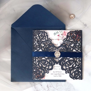 Détail de l'invitation découpée au laser avec carte florale et ruban en strass bleu