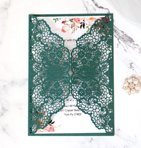 Detail of laser-cut forest green wedding invitation with elegant floral lace pattern