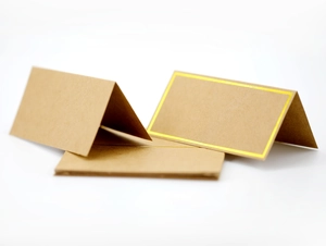Close-up of brown kraft paper place cards with elegant gold foil borders for weddings
