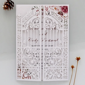Laser-cut white wedding invitation with elegant floral lining and gate design detail