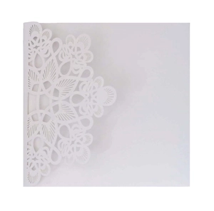 Detailed close-up of intricate laser-cut white floral pattern on a wedding invitation card