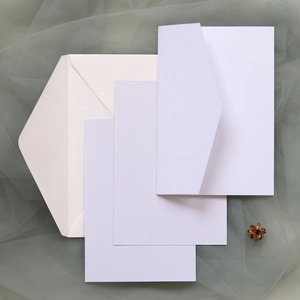 Détail des invitations lavande découpées au laser avec enveloppes ivoire sur un fond de tulle
