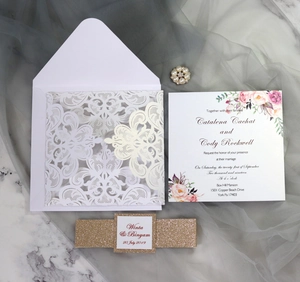 Elegant white laser-cut wedding invitation set with floral card and gold glitter band