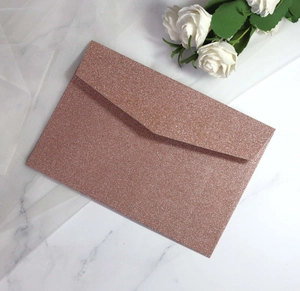 Rose gold glitter envelope with V-flap on white marble background with flowers