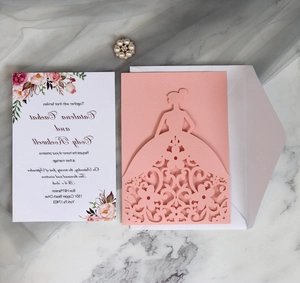 Detail of laser-cut wedding invitation featuring a pink gown design and floral inner page