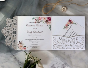 Macro detail of laser cut wedding invitation with floral insert card on marble background