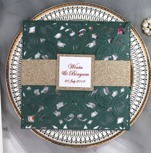 Detail of dark green laser-cut wedding invitation with glitter belly band and white card