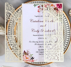 Detailed laser-cut ivory wedding invitation with floral inner card on porcelain plate
