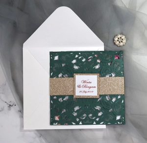 Elegant laser-cut dark green wedding invitation set with gold band on marble background