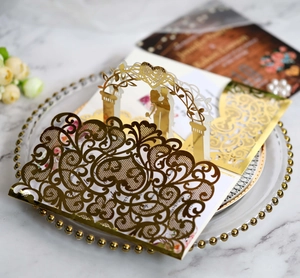 Detail of laser cut gold glitter wedding invitation with 3D pop-up couple silhouette