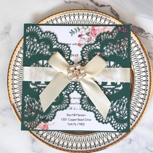 Deep green laser-cut wedding invitation card with ribbon and pearl floral accent