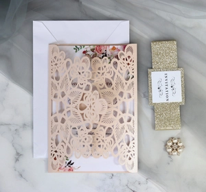 Macro detail of laser-cut wedding invitation set with pearl buckle and golden belt