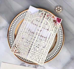 Detail of laser-cut wedding invitation featuring intricate floral lace and ivory inner page