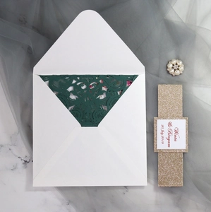 Detail of dark green laser-cut wedding invitation with gold glitter belly band and envelope