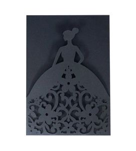 Detail of laser-cut wedding invitation showing intricate floral patterns on a black gown silhouette